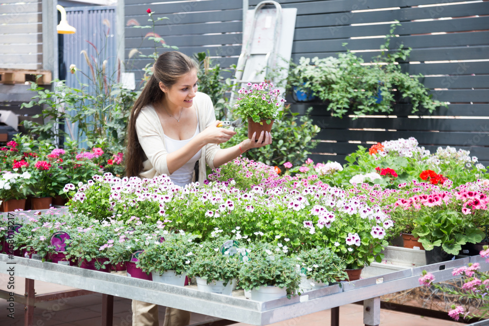 european young woman working with potted flowers in botanical shop