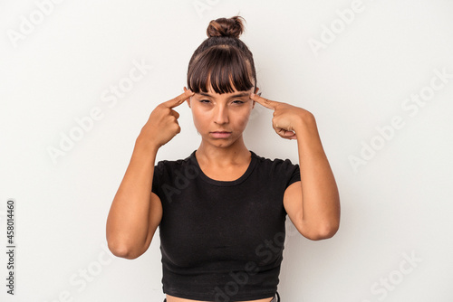 Young mixed race woman isolated on white background focused on a task, keeping forefingers pointing head.