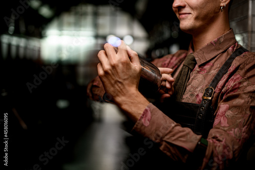 male hands of bartender holds steel shaker and shake it