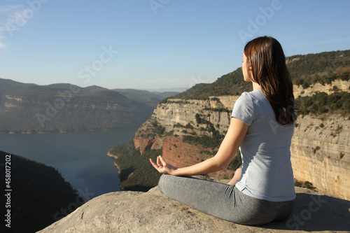 Woman doing yoga on the top of a cliff
