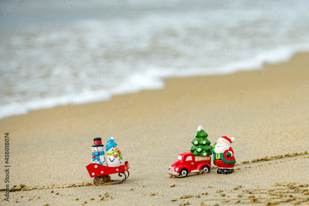 Christmas background. Toy Santa and snowman on summer beach, concept for travel in hot countries.
