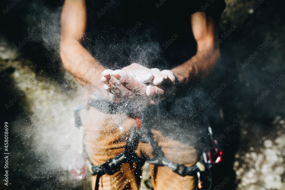 Fototapeta premium Climber man coating his hands in powder chalk magnesium. Ready for climbing
