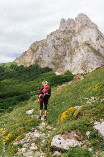Young female traveler, with a backpack on her back, ascending a mountain during an excursion through the Picos de Europa National Park.