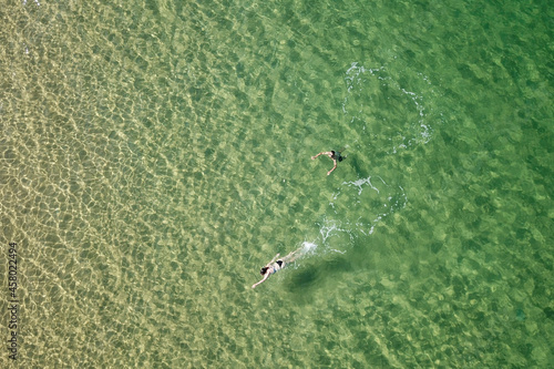 Top view of two swimmers, a boy and a girl in a turquoise sea