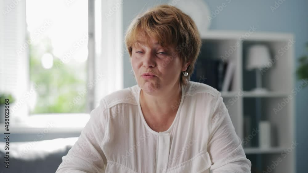 Retired woman in casual wear sitting at living room, talking and gesturing during video call. Concept of distance communication. First person view. Retired woman in casual wear sitting at living room, talking and gesturing during video call. Concept of distance communication. First person view.