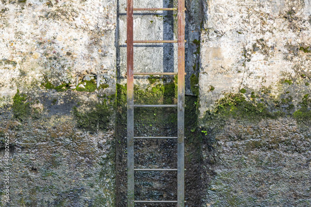 Metal staircase made of rusty rebar against the background of weathered cracked concrete wall Metal staircase made of rusty rebar against the background of weathered cracked concrete wall