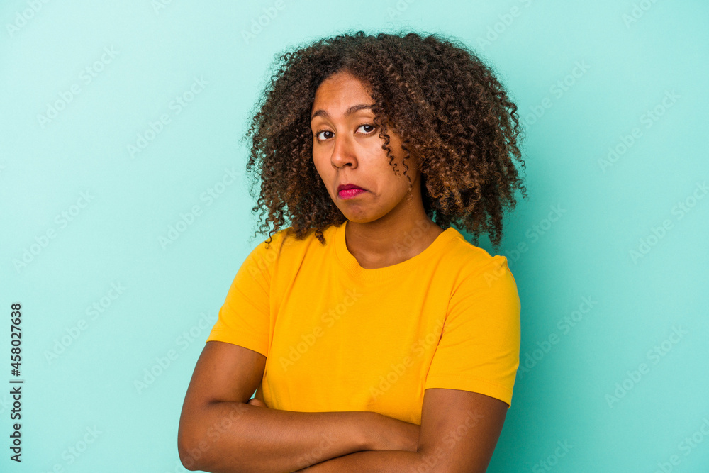 Young african american woman with curly hair isolated on blue background unhappy looking in camera with sarcastic expression. Young african american woman with curly hair isolated on blue background unhappy looking in camera with sarcastic expression.