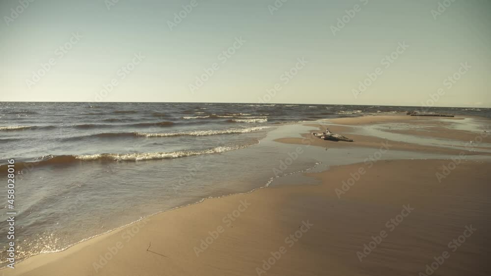 Sea shoreline with sand banks and waves crashing over them in golden evening light Sea shoreline with sand banks and waves crashing over them in golden evening light