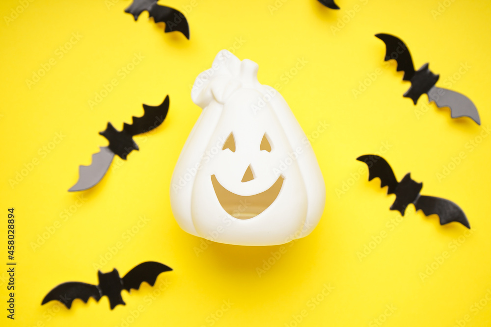 White halloween pumpkin and bats on a yellow background, flat lay. Halloween concept.