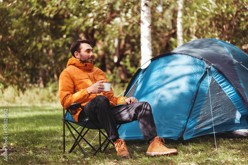 Fotografering camping, tourism and travel concept - happy man drinking tea at tent camp