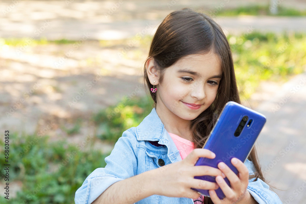 Happy child girl with phone outdoors. Gagets consept Happy child girl with phone outdoors. Gagets consept
