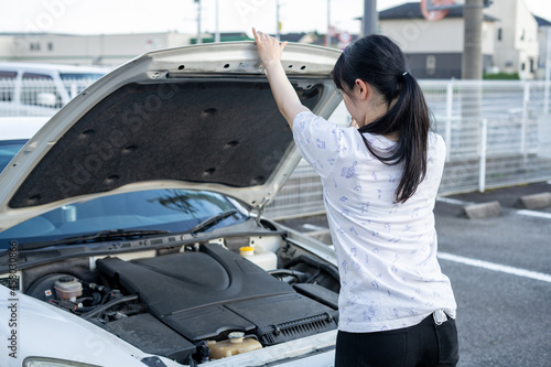 車のボンネットを開ける女性 © Haru Works