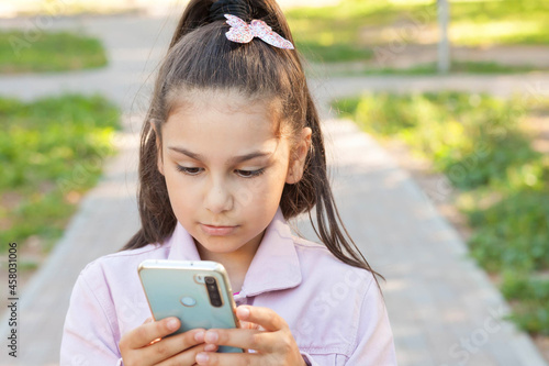 Happy child girl with phone outdoors. Gagets consept