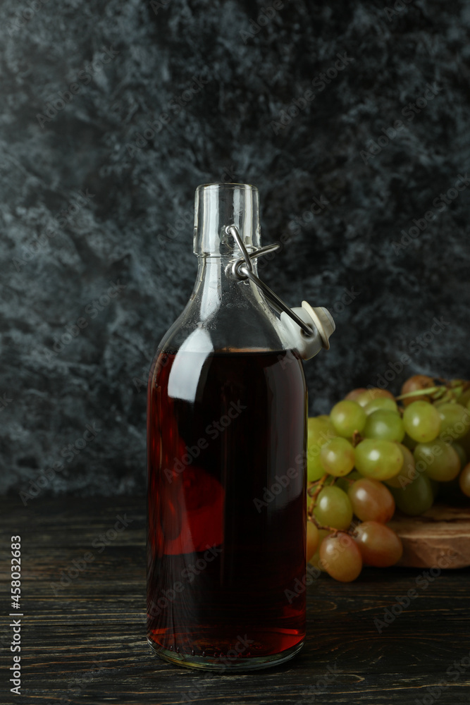 Bottle of vinegar and grape on rustic wooden table