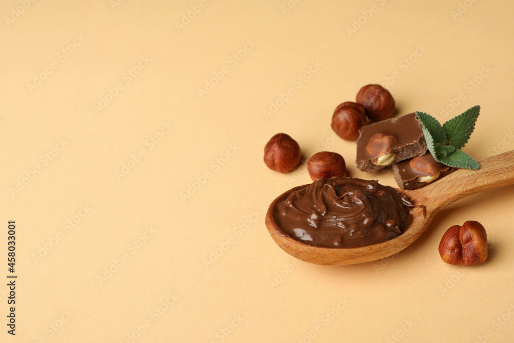 Spoon with chocolate paste, nuts, chocolate and mint on beige background Spoon with chocolate paste, nuts, chocolate and mint on beige background