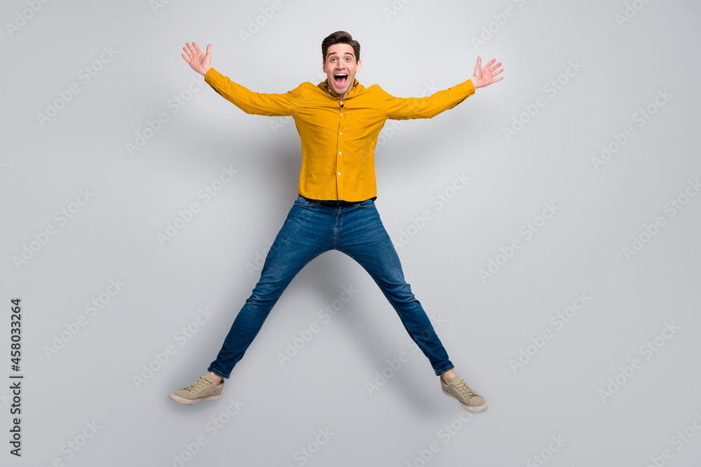 Full length body size view of attractive cheerful energetic man jumping having fun isolated over grey color background