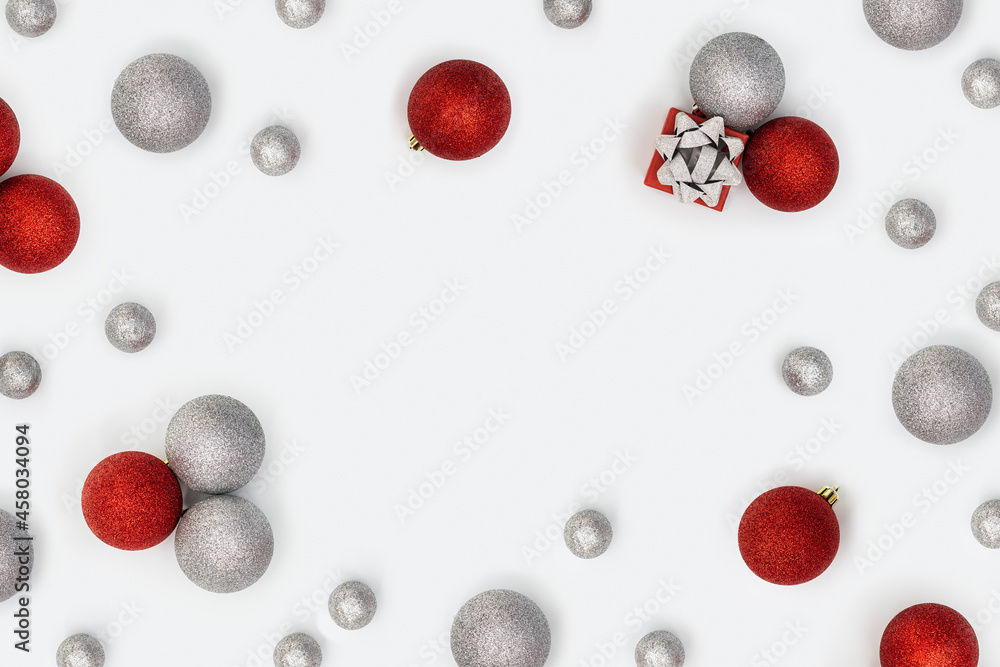 Christmas frame with sparkly red and silver Christmas balls and small gift box or present on white background. New Year holiday decorations with copy space. Christmas frame with sparkly red and silver Christmas balls and small gift box or present on white background. New Year holiday decorations with copy space.