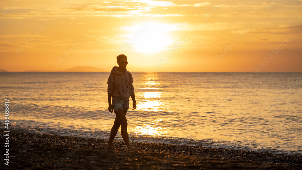 Happy carefree woman enjoying beautiful sunrise on the beach. Yellow sun over sea. Orange colors waves. Nature background. Beautiful serene scene. Morning.