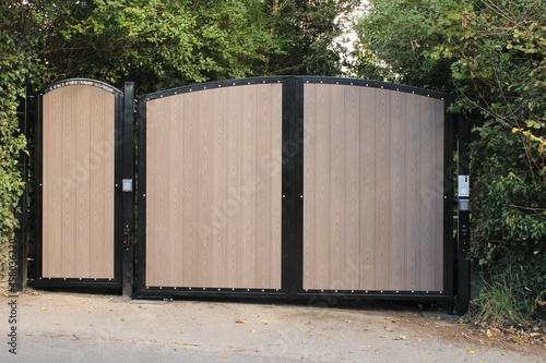 Newley installed modern residential wooden and metal electric security gates with keypad
