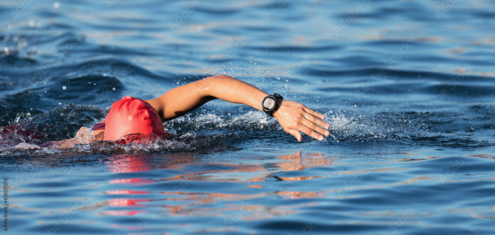Woman swimmer swimming crawl in blue sea, race for triathlon