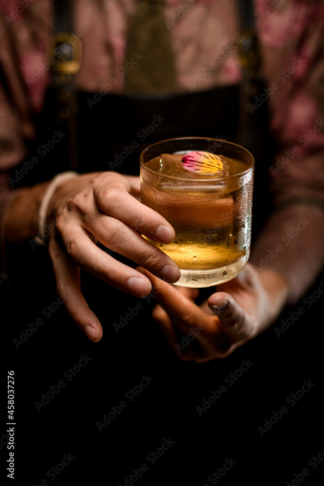 hands of man accurate holds glass of cocktail decorating with beautiful flower petal hands of man accurate holds glass of cocktail decorating with beautiful flower petal