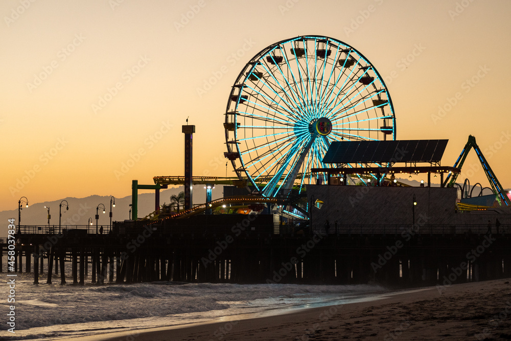 The Ferris wheel of the famous Santa Monica Pier at sunset on the beach in Los Angeles
