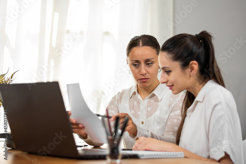 Mujeres de negocio corroboran datos en un papel mientras trabajan en la oficina.