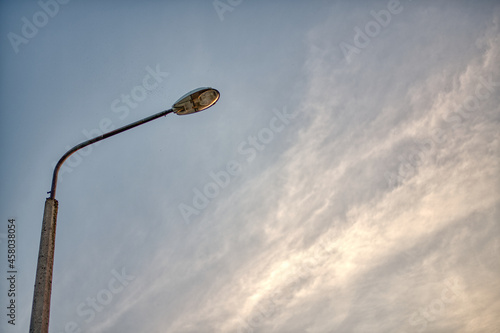 Old street lamp with blue sky and clouds in background. photo