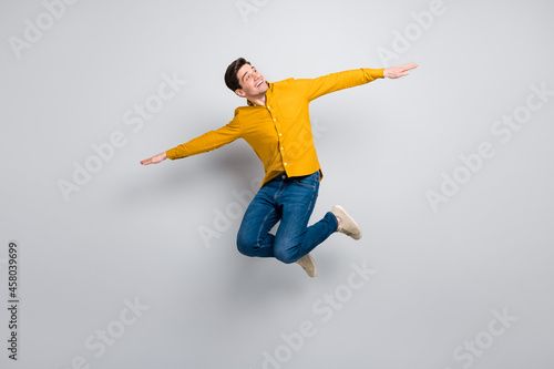 Full length body size view of attractive cheerful man jumping flying like plane isolated over grey color background