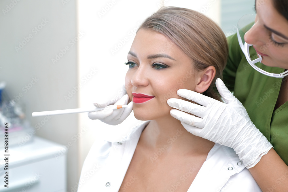 Young woman having permanent makeup on her lips at the beauticians salon. Young woman having permanent makeup on her lips at the beauticians salon.