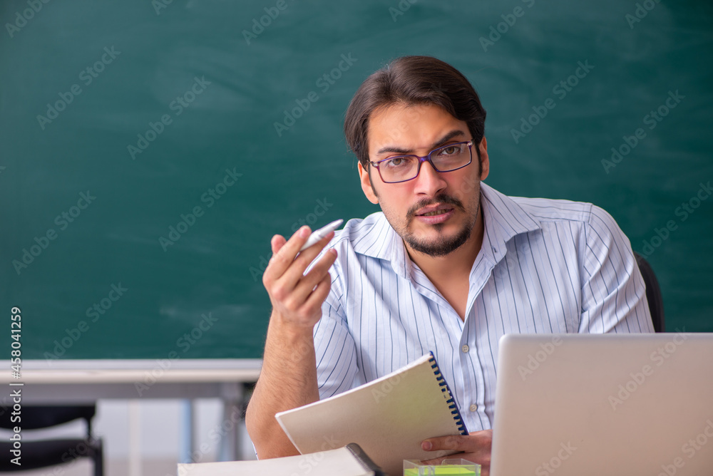 Young male teacher in front of blackboard Young male teacher in front of blackboard
