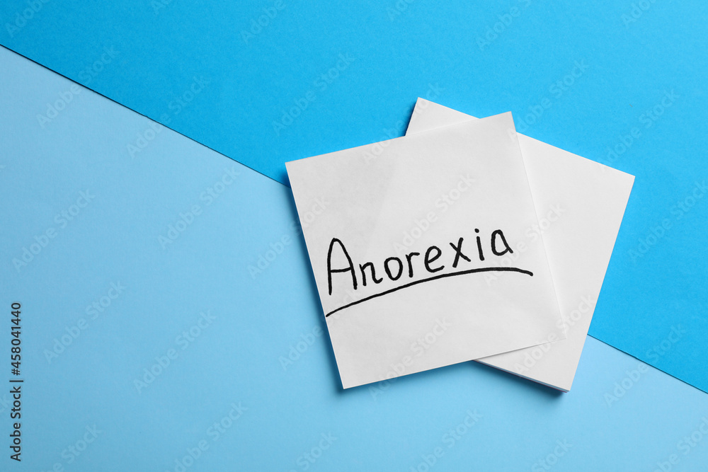 Note papers with word Anorexia on light blue background, flat lay. Space for text Note papers with word Anorexia on light blue background, flat lay. Space for text