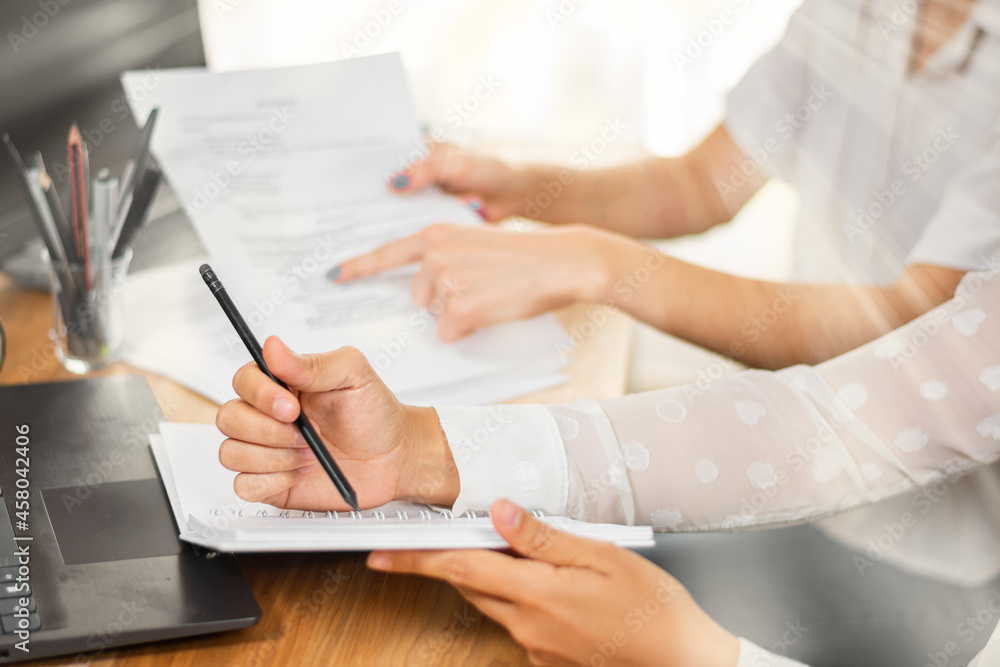 Ταπετσαρία Mujer de negocios escribe en su agenda mientras conversa con su compañera de trabajo en la oficina