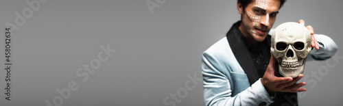 blurred man in halloween makeup showing spooky skull isolated on grey, banner © LIGHTFIELD STUDIOS