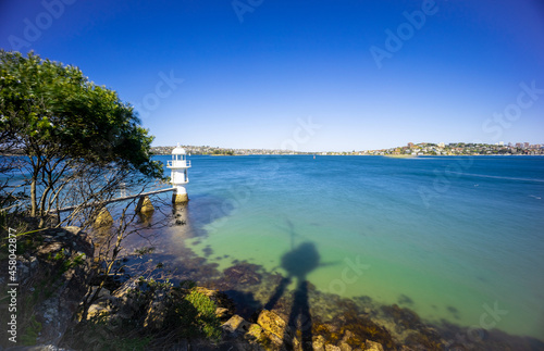 Sunny Spring day on Sydney Harbour with nice rocks in the foreground the soft waves crashing on the shore and the beautiful harbour foreshore as a backdrop NSW Australia