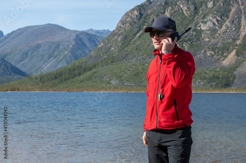 man talking on a satellite phone in the mountains