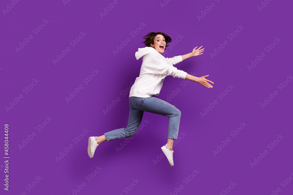 Full size profile side photo of young excited smiling female running in air catch hold product isolated on violet color background Full size profile side photo of young excited smiling female running in air catch hold product isolated on violet color background