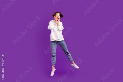 Full size photo of young good mood crazy amazed girl jump hear unexpected news isolated on violet color background