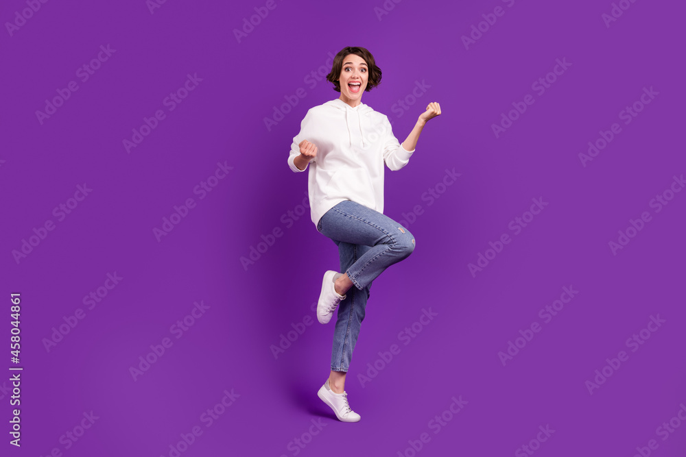 Full size photo of young excited good mood girl raise fists in victory triumph isolated on violet color background