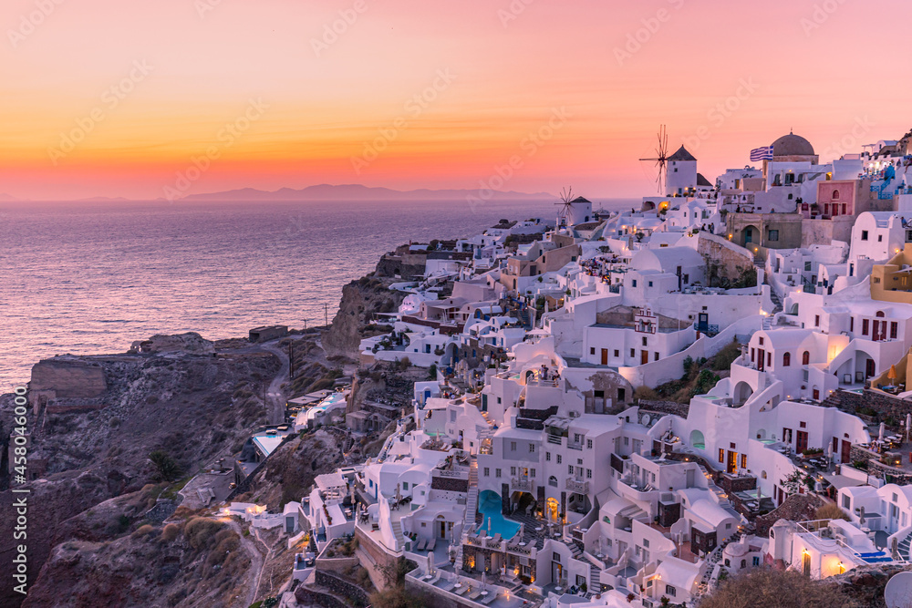 Oia village at night, Santorini island. Famous travel landscape, luxury vacation destination scenic. Beautiful view of fabulous picturesque village colorful sky, traditional white houses and windmills