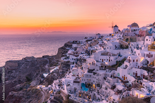 Oia village at night, Santorini island. Famous travel landscape, luxury vacation destination scenic. Beautiful view of fabulous picturesque village colorful sky, traditional white houses and windmills © icemanphotos