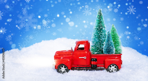 A red truck carries Christmas trees through the snow