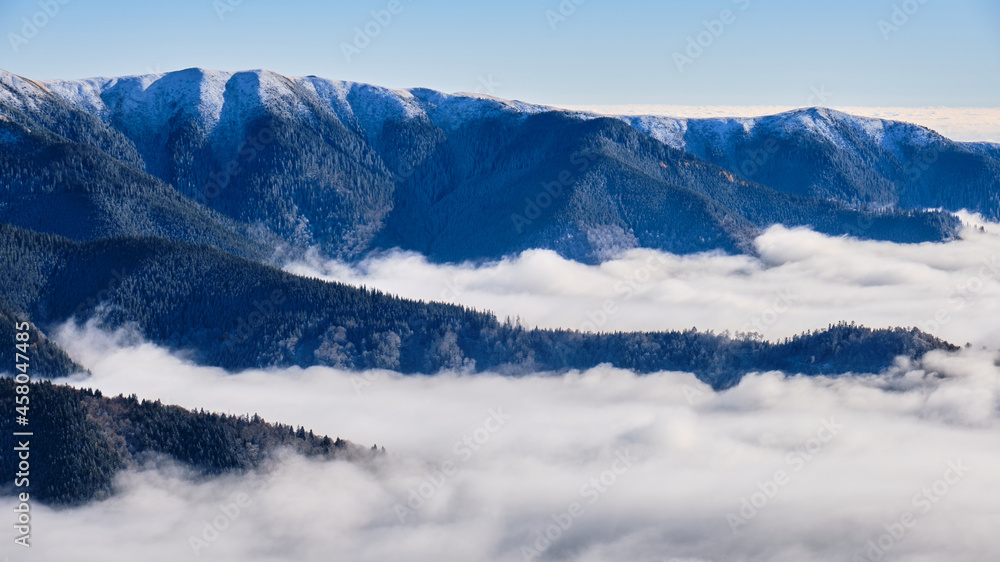 Sea of clouds in the mountains created by temperature inversion. View towards Bucegi mountains (part of Carpathian mountains), Romania. Layers, Winter, scenery, scenic.