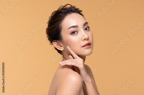 Beautiful Asian young woman touching soft cheek smile with clean fresh skin Happiness and cheerful with positive emotional,isolated on Beige background,Beauty Cosmetics and Facial treatment Concept