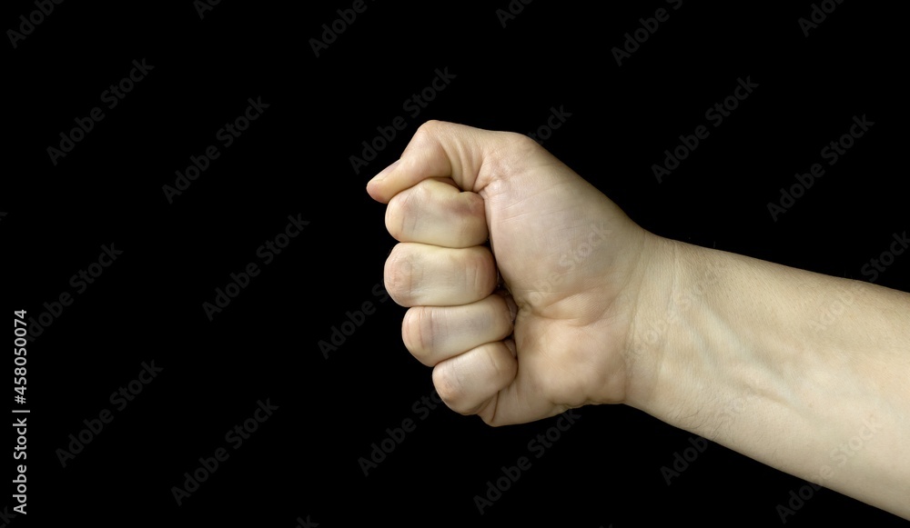 Clenched fist on a black background, Aggressiveness, masculinity, the concept of challenge Clenched fist on a black background, Aggressiveness, masculinity, the concept of challenge