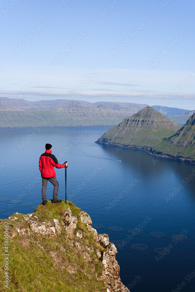Hiker in hike on Eysturoy island overlooking the Funningur fjord, Faroe Islands