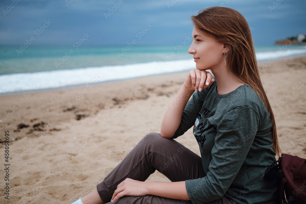 woman enjoying sea air on autumn beach before thunderstorm woman enjoying sea air on autumn beach before thunderstorm