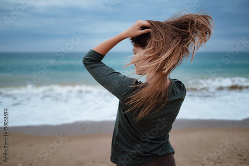 woman enjoying sea air on autumn beach before thunderstorm