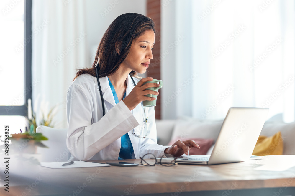 Attractive female doctor talking while explaining medical treatment to patient through a video call with laptop in the consultation. Attractive female doctor talking while explaining medical treatment to patient through a video call with laptop in the consultation.