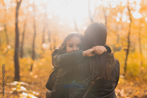 Mother and daughter spend time together in autumn yellow park. Season and single parent concept.